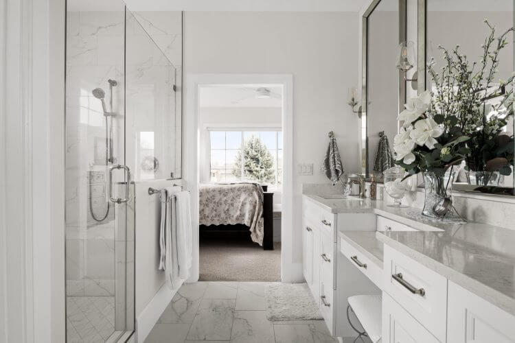 A bathroom with elegant marble counter tops and pristine white cabinets. Expertly remodeled by Pleasant Grove Utah Custom Home Remodelers.