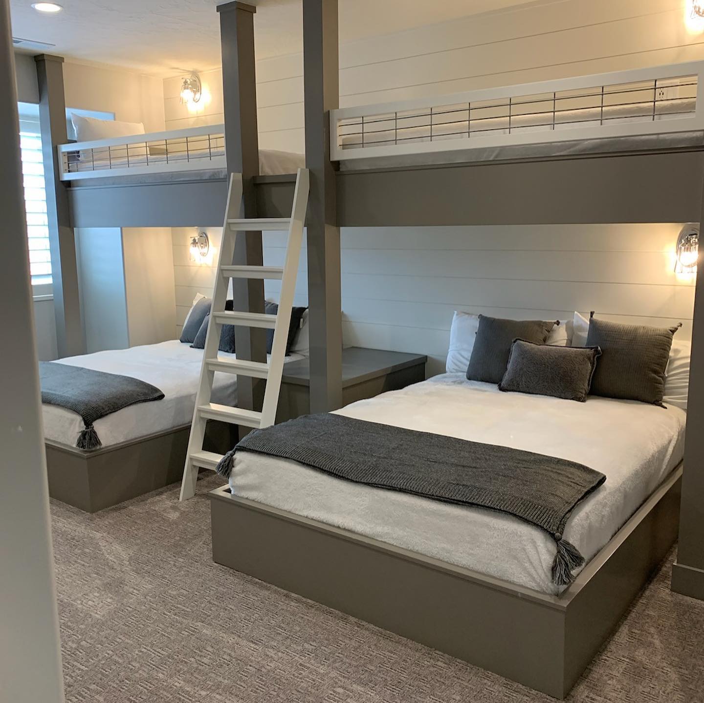 Two bunk beds in a room with white walls, simple and functional furniture for shared sleeping space